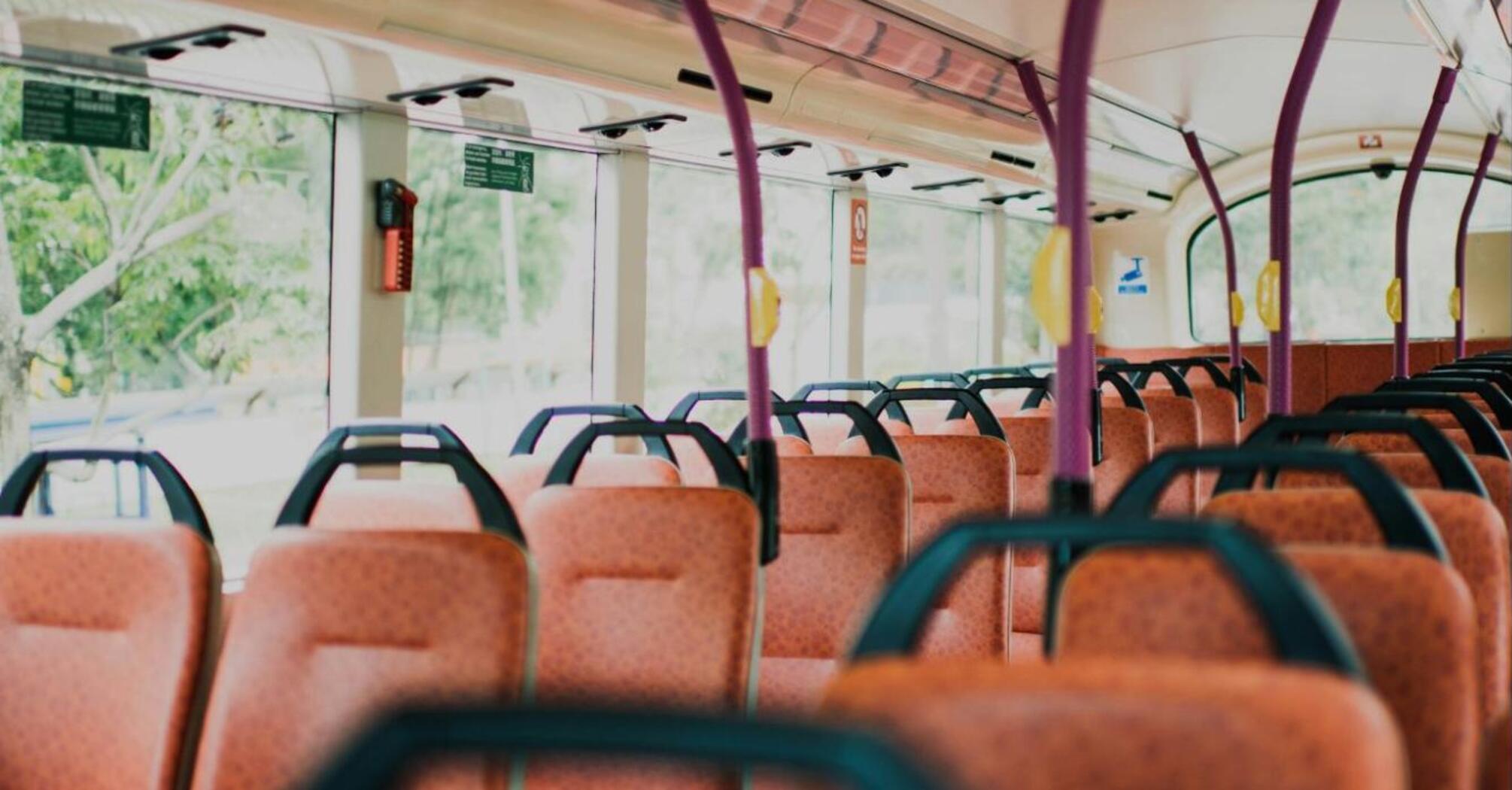 Interior of an empty bus with orange seats and purple handrails