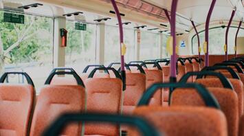 Interior of an empty bus with orange seats and purple handrails