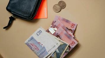 Wallet with cash, coins, and a card on a table