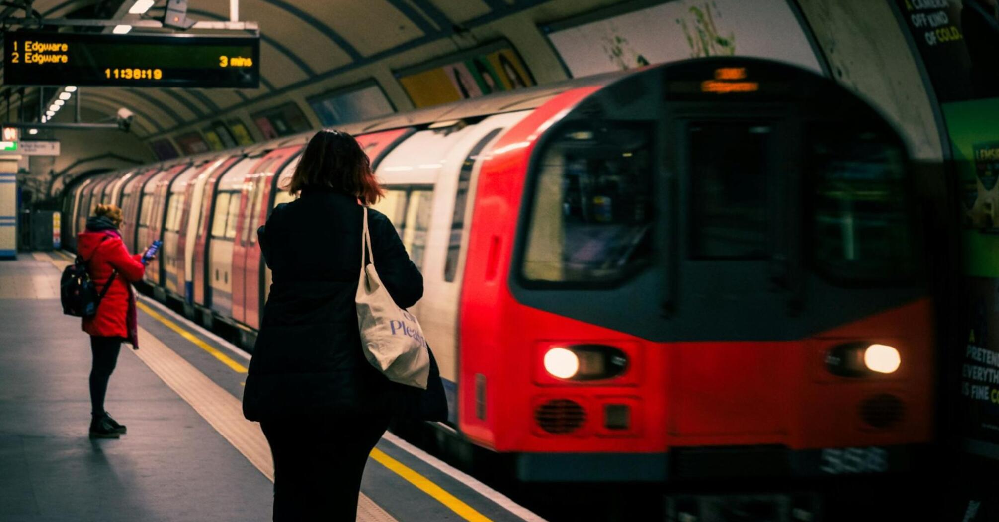 A red and white London Underground train at a station with passengers waiting on the platform