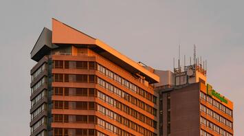 Concrete, modernist, brutalist Holiday Inn Kensington bathed in golden sunset light.