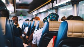 Passengers seated on a bus, viewed from the back