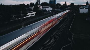 A train speeding through a suburban area during twilight