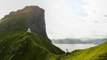 Man standing on a green mountain on Kalsoy Island