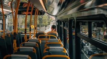 Interior of a bus with empty seats and a passenger in the distance
