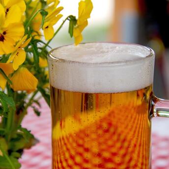 A glass of light beer against a backdrop of bright flowers