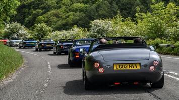 Cars driving on a road through a lush green forest in the Peak District