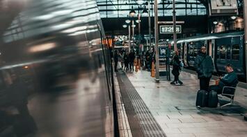 Busy train station platform with passengers waiting beside a modern train