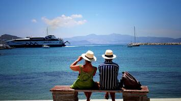 Couple of travelers on the bench beside the sea in Greece