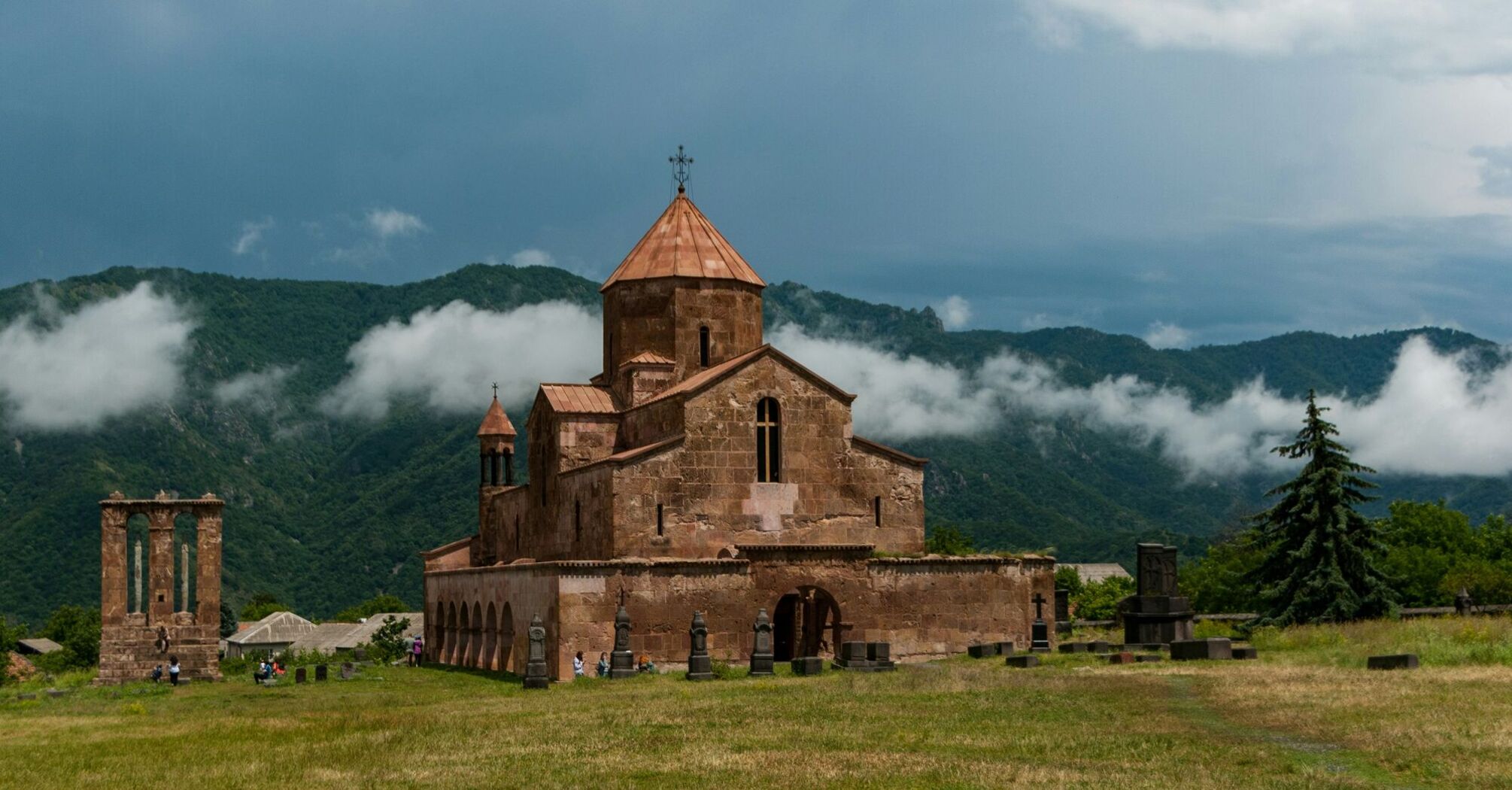 brown concrete church on green grass field under white clouds during daytime