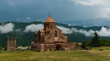 brown concrete church on green grass field under white clouds during daytime
