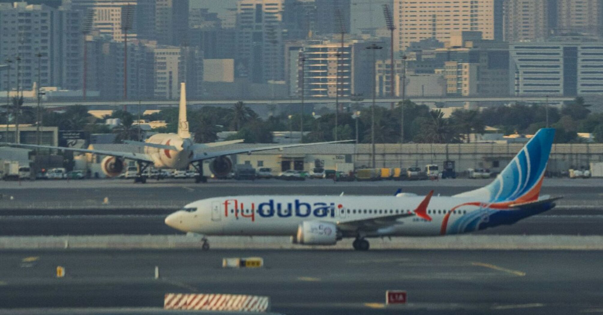 Flydubai airplane on runway with city skyline in background