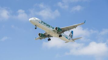 Frontier Airlines aircraft in flight against a blue sky