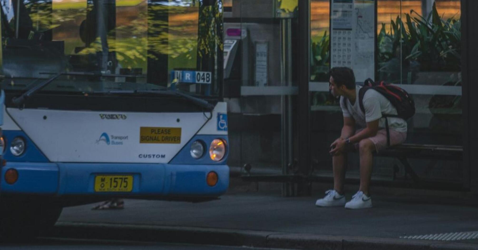 A bus with a passenger waiting at the bus stop