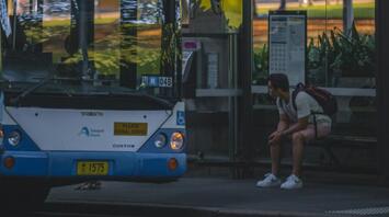 A bus with a passenger waiting at the bus stop