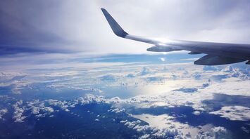 Airplane wing over clouds and coastline