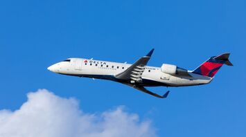 Delta Connection plane in flight against a blue sky