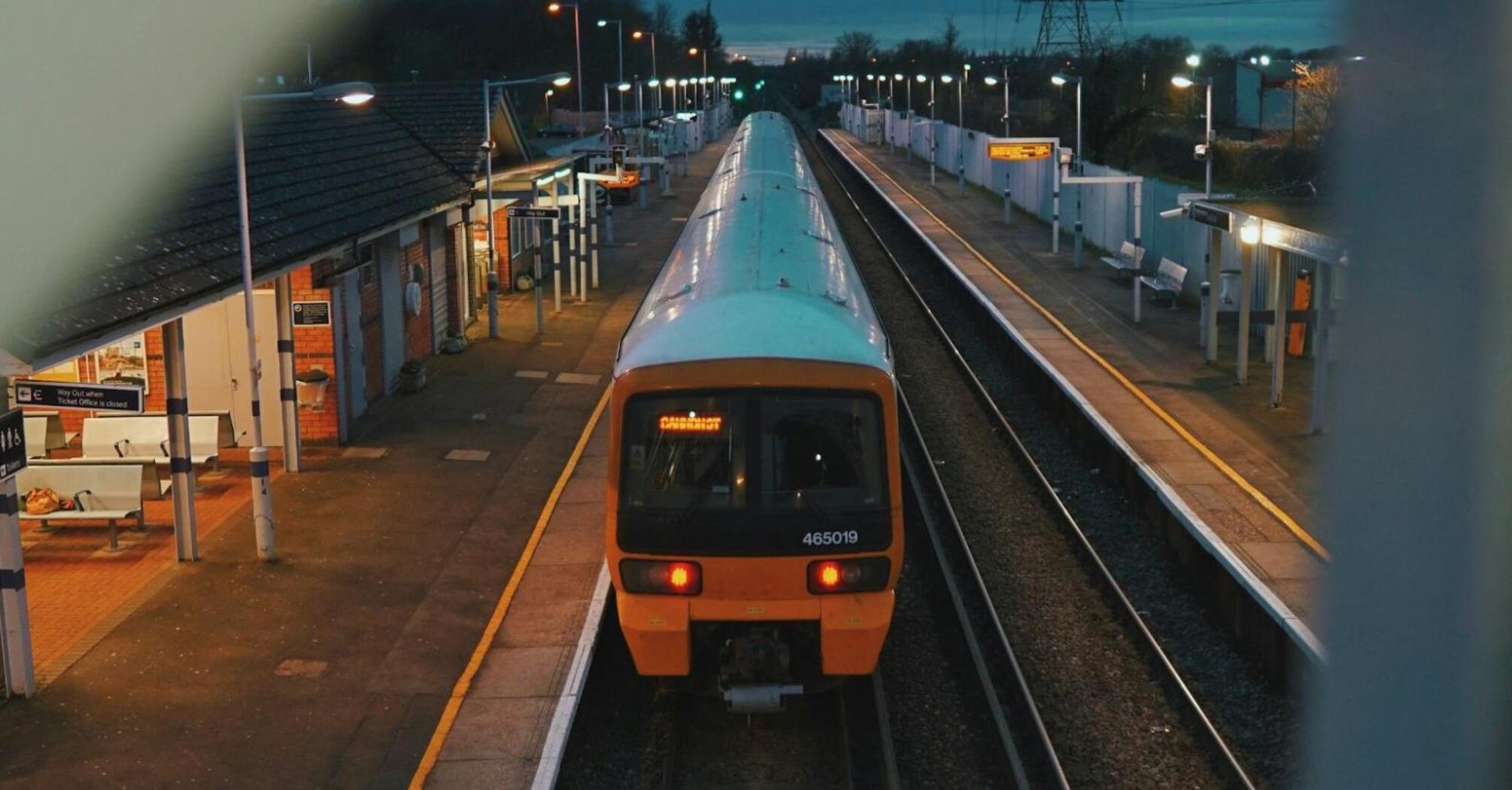 A train at a dimly lit station platform during the evening