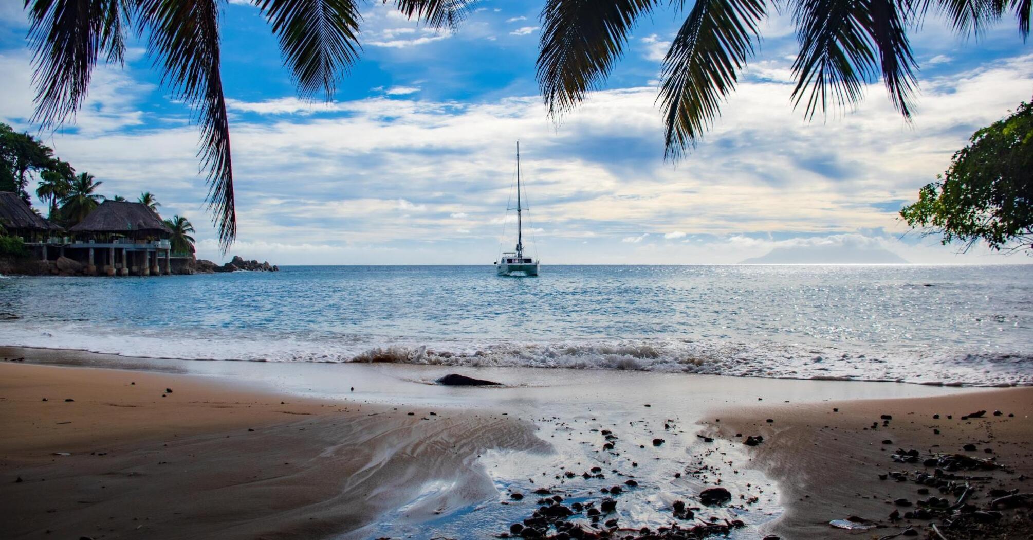 A quiet morning on a tropical beach with a view of a yacht floating on the horizon