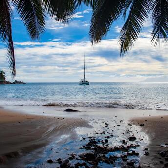 A quiet morning on a tropical beach with a view of a yacht floating on the horizon