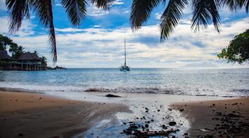 A quiet morning on a tropical beach with a view of a yacht floating on the horizon