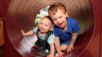 Two little children having fun playing in a tunnel at the playground
