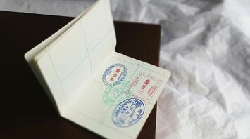a foreign passport with stamps inside lies on the bed