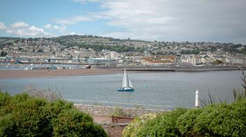 View of a Torbay city with sailboats in the water and houses on the hills
