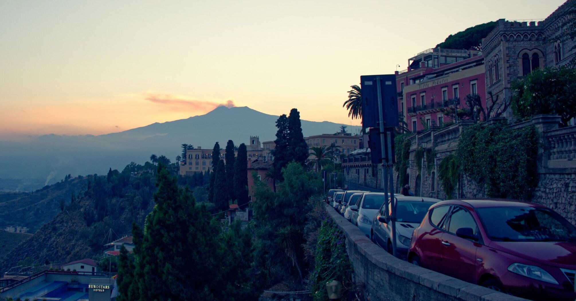 View of a hillside town in Italy with mountains in the background at sunset