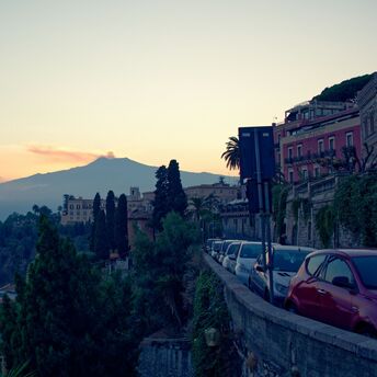 View of a hillside town in Italy with mountains in the background at sunset
