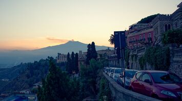 View of a hillside town in Italy with mountains in the background at sunset