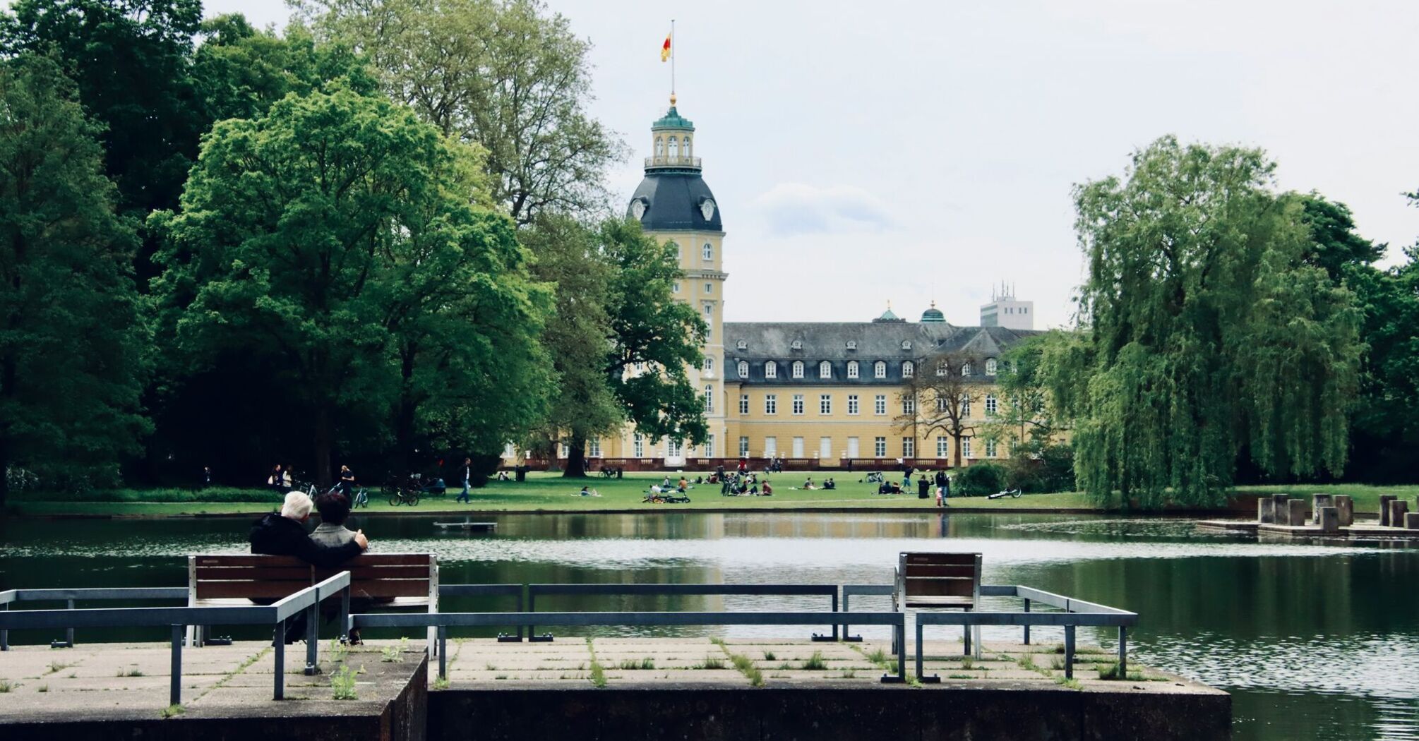 people sitting on bench near body of water during daytime in Karlsruhe