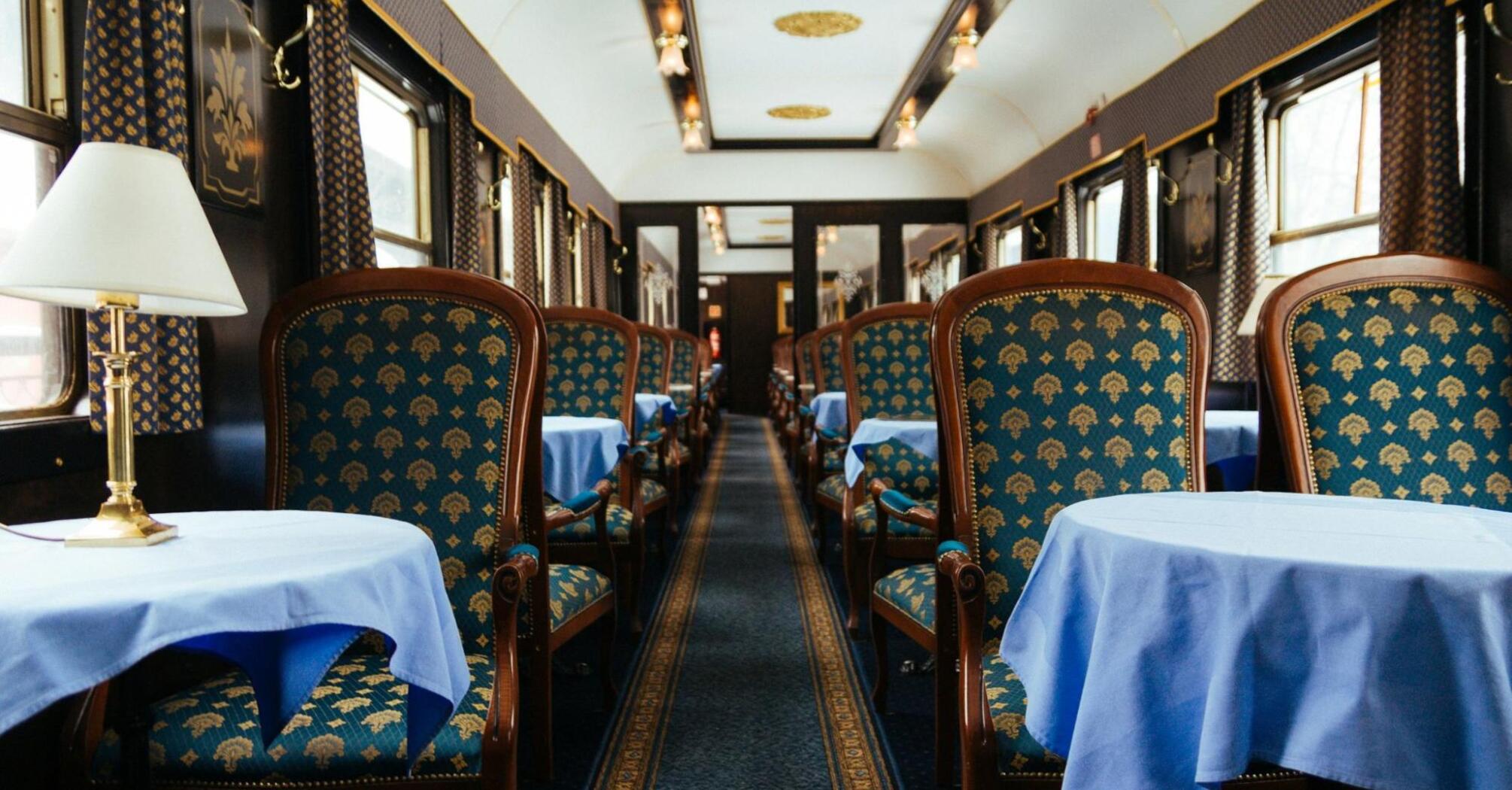 A luxurious vintage train dining car with elegant blue and gold furnishings