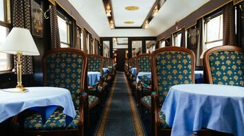 A luxurious vintage train dining car with elegant blue and gold furnishings