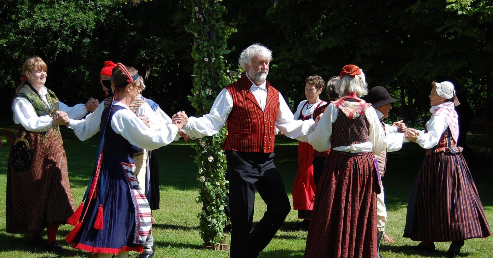 People celebrating the midsummer with traditional folk dance