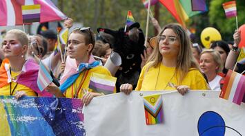 Participants at the Pride parade hold various LGBTQ+ flags and banners