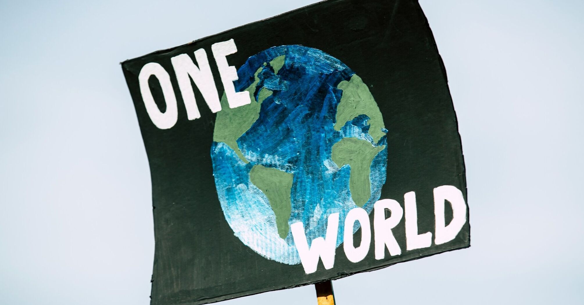 Sign reading 'One World' with a painted globe
