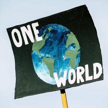 Sign reading 'One World' with a painted globe