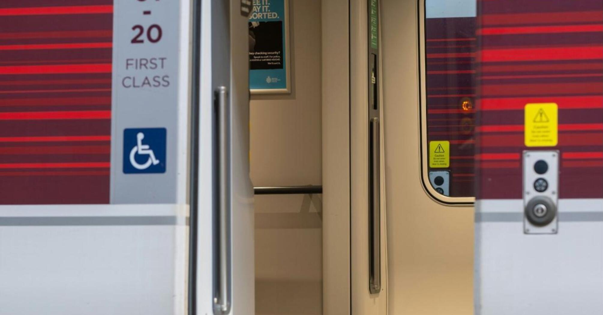 Open door of a first-class train carriage with wheelchair accessibility symbol at a train station platform