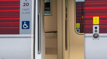 Open door of a first-class train carriage with wheelchair accessibility symbol at a train station platform