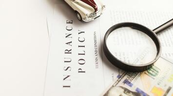 Insurance policy document with magnifying glass and toy car