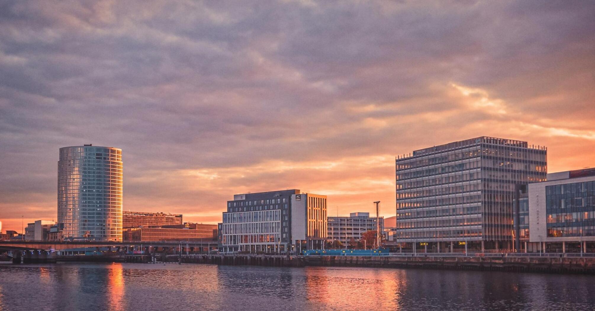 Sunset over the Belfast waterfront with modern buildings reflecting on the water