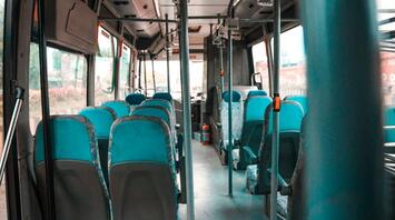 Empty interior of a public bus with blue seats and metal handrails