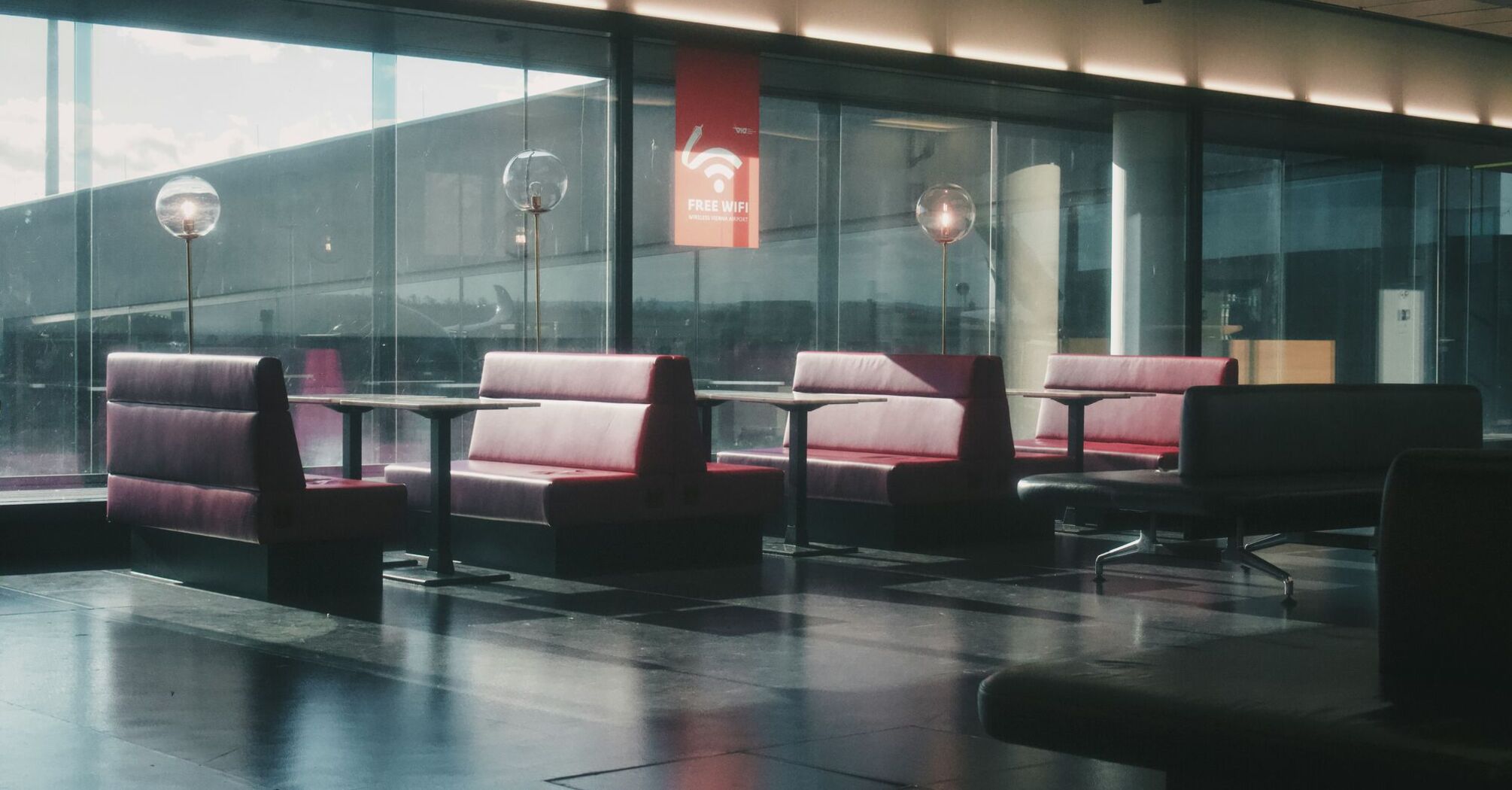 a waiting area with chairs and tables in front of large windows