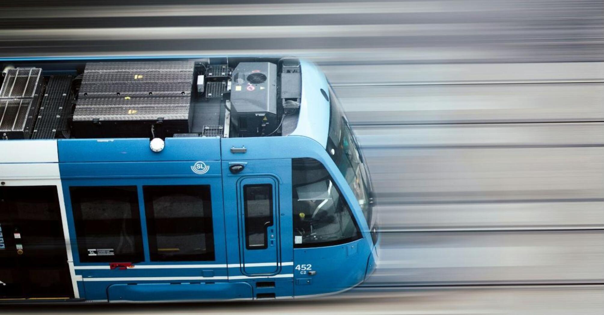 A blue train speeding along railway tracks in Sweden