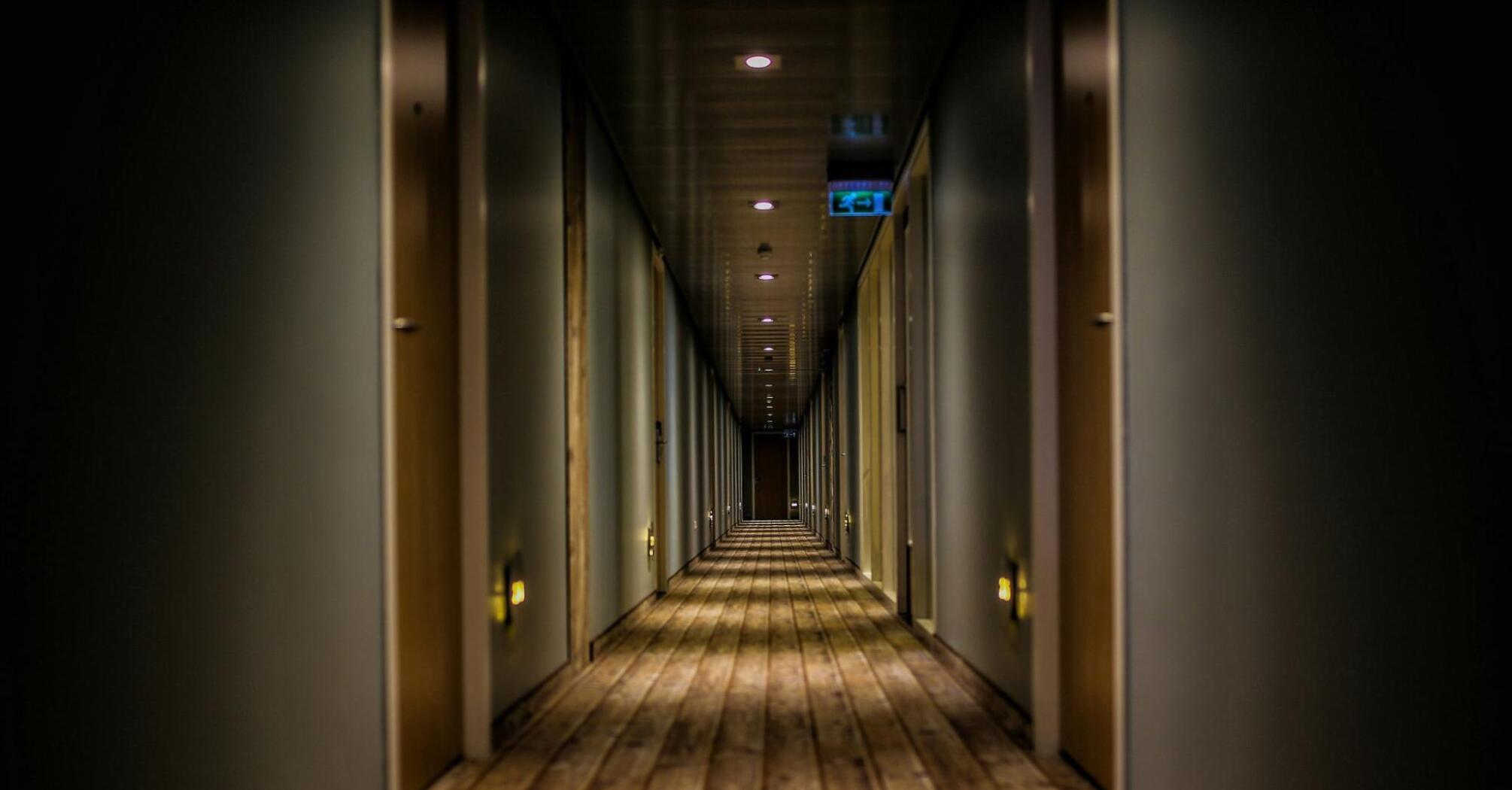 A long corridor with a wooden floor and rows of closed doors