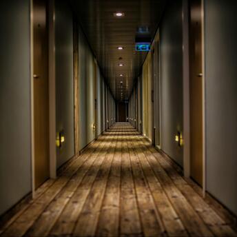A long corridor with a wooden floor and rows of closed doors
