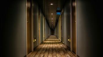 A long corridor with a wooden floor and rows of closed doors