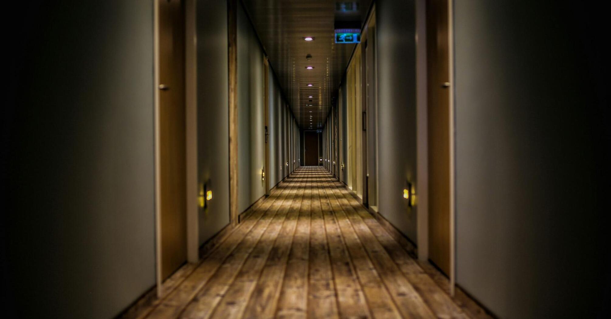 A long corridor with a wooden floor and rows of closed doors