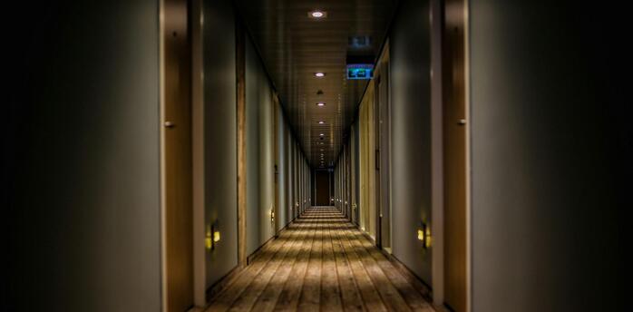 A long corridor with a wooden floor and rows of closed doors